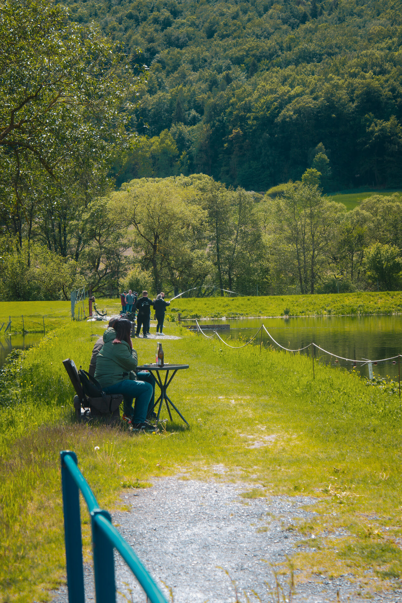 Einzelner Angler in Regenkleidung am Forellenteich, von hinten